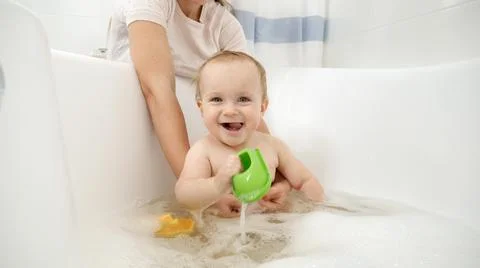 Happy smiling baby boy playing with toys and washing in bath Stock Photos