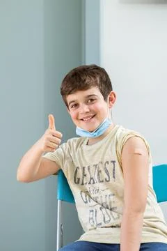 Happy smiling boy looking at camera showing thumb up after vaccination. Stock Photos