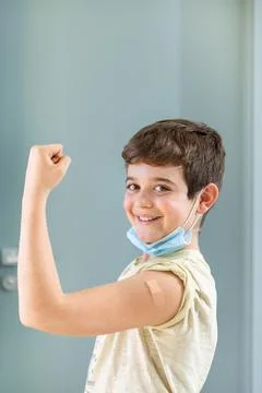 Happy smiling boy looking at camera showing proud vaccinated arm. Stock Photos