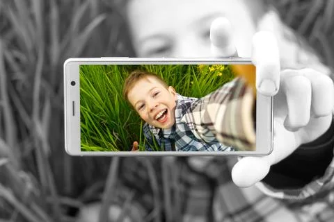 Happy smiling boy making self portrait on smartphone in meadow. young boy making Stock Photos