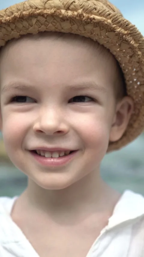 Happy smiling boy in a straw hat at the beach on a sunny summer day, cheerful 库存影片 347101774