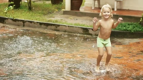 Happy smiling child having fun in the rain. Boy running through puddle. Stock Footage 56141141