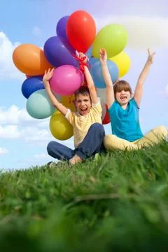 Happy smiling children lying on the green grass with colorfull balloons in th Foto stock