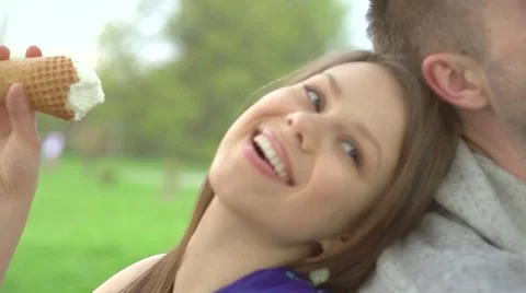 Happy smiling couple eating ice cream and relaxing on green grass in a park 動画素材 59081906