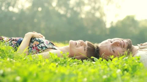 Happy smiling couple lying on grass and relaxing HD Stock Footage 8573098