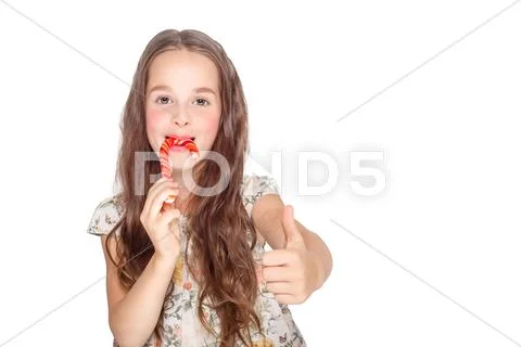Happy, smiling cute little girl eating cristmas candy cane. Isolated on white Stock Photos