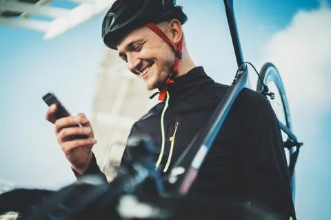 Happy smiling cyclist man using modern smartphone outside Stock Photos