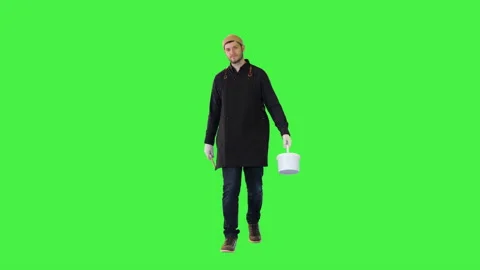 Happy smiling decorator man walk with bucket of paint and paintbrush Young Stock Footage 157330260