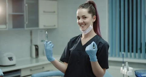 Happy smiling dentist nurses assistant preparing a surgical syringe for a Stock Footage 101736376