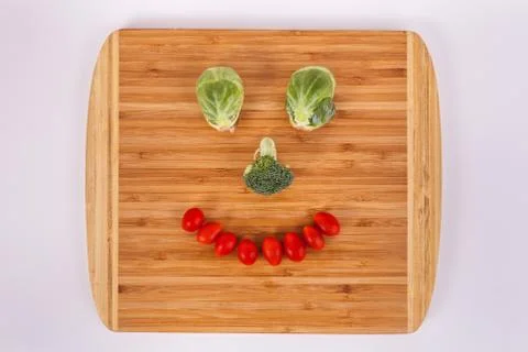 Happy smiling face made with vegitables in bamboo cuttingboard Stock Photos