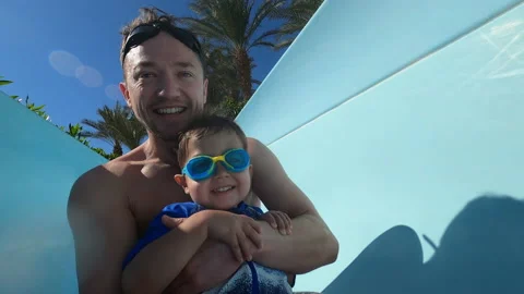 Happy smiling father rolling down the water slide with his little kid son Stock Footage 169748430
