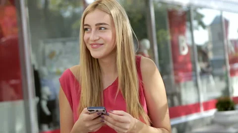 Happy smiling girl using her mobile phone near fashionable boutique Stock Footage 55391049
