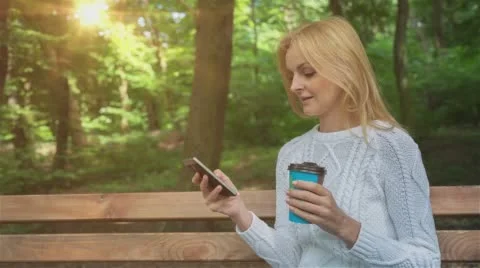 Happy smiling girl using a smart phone in a city park sitting on a bench 5 Stock Footage 65454315