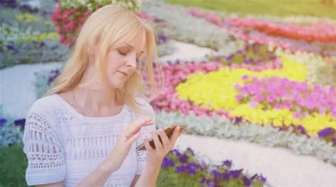 Happy smiling girl using a smart phone in a city park sitting on a bench 6 Stock Footage 66256475