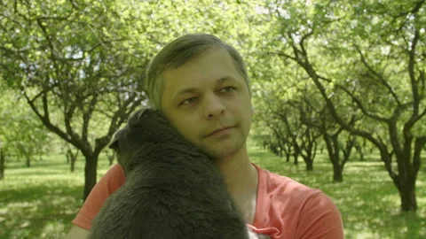 Happy smiling handsome man Stroking a Cat and walks through green trees alley 库存影片 110788209