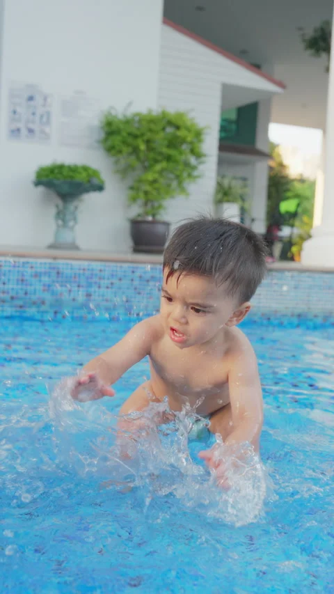 Happy smiling kid playing splash the water in swimming pool on summer vacation. Stock Footage 241393707