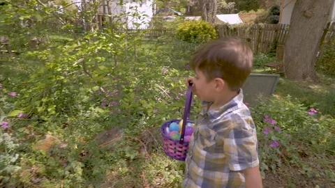 Happy smiling little boy finding easter eggs during a easter egg hunt Stock Footage 83146306