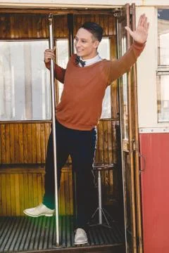 Happy smiling man in wagon train or tram holds rod  and waving Stock Photos