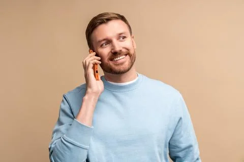 Happy smiling middle aged man talking calling phone on beige background looking Stock-Fotos