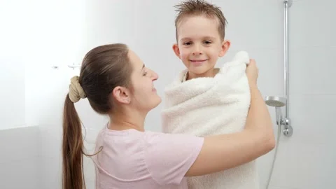 Smiling young girl bathing under a shower at home. Beautiful teen girl  taking shower and washing in the bathroom. Happy child washing head, face  and body with water. Stock Video