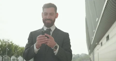 Happy Smiling Office Manager walking in the City while Using his Smartphone Video stock 131345459