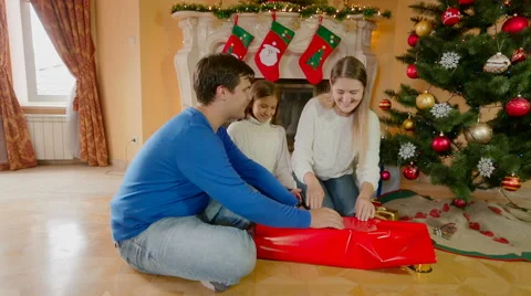 Happy smiling parents with daughter wrapping present for Christmas Stock Footage