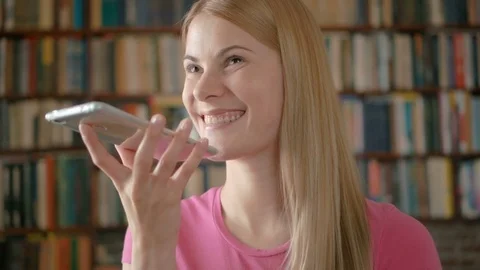 Happy smiling student standing in library using her smartphone, chatting with Video stock 75334604