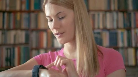 Happy smiling student standing in library using smartwatch, browsing, reading Stock Footage 75334637
