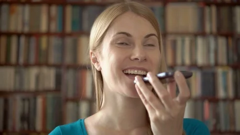 Happy smiling student standing in library using her smartphone, chatting with Stock Footage 75409976