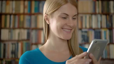 Happy smiling student standing in library using smartphone, browsing, reading Stock Footage 76023257