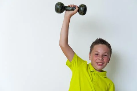 Happy smiling tween boy lifting dumbbell Stock Photos