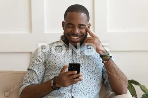 Happy smiling young african american guy holding cell phone. Stock Photos