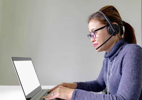 Happy smiling young asian support phone operator in headset with laptop, on g Stock Photos