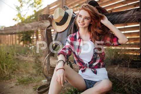 Happy smiling young cowgirl resting at the ranch fence Stock Photos