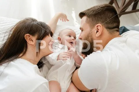 Happy smiling young family in bed with infant Stock Photos