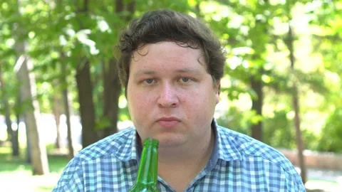 Happy smiling young man drinking beer at outdoor park in summer Stock Footage 95614186