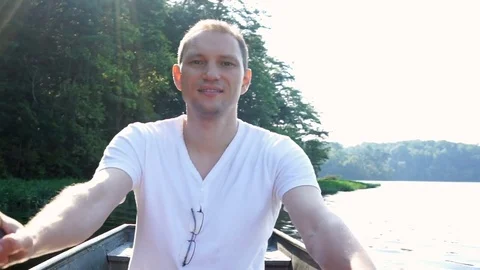 Happy smiling young man rowing boat on lake in Virginia during summer with sun Stock Footage 80206525