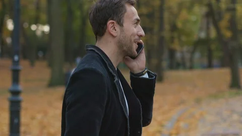 Happy smiling young man use talk phone in the park grass telephone speak Stock Footage 102728490