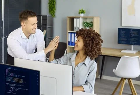 Happy software developers high five over solved code in modern office workspace Stock Photos