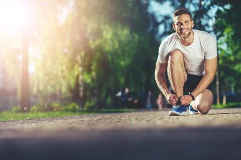 Happy sprinter tying snickers during running Foto stock