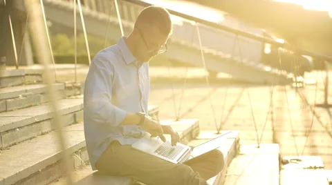 Happy student browsing the internet on his laptop and sitting outdoor Stock Footage 68074162