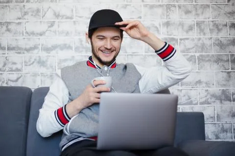 Happy student guy using laptop with cup of coffee. Stock Photos