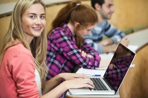 Happy student sitting in a lecture using her laptop Foto stock