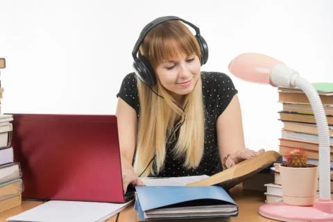 Happy student sitting at the table and preparing for exams in headphones Stock Photos
