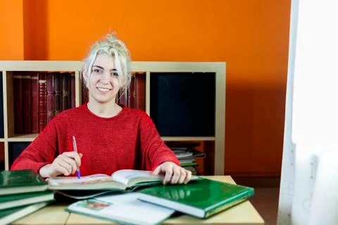 Happy student smiling while studying and looking at camera Fotos de archivo