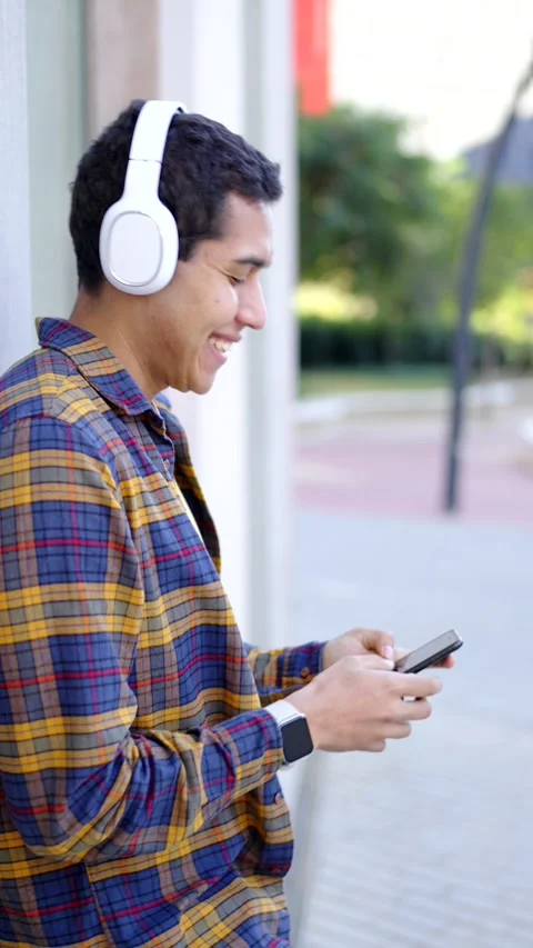 Happy student using phone and laughing leaning on a wall Stock Footage 258325452
