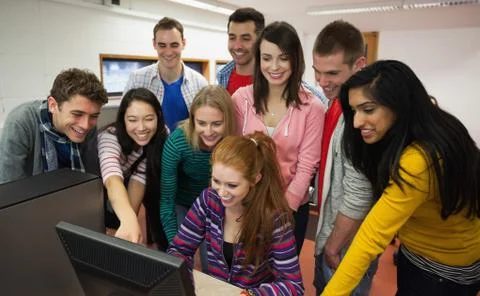 Happy students looking at computer in the computer room Stock Photos
