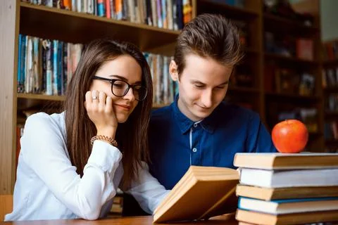 Happy students reading a book in the library together Stock Photos