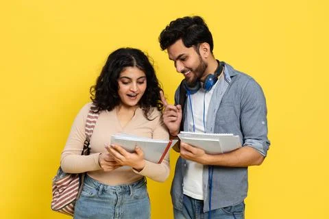 Happy Students Sharing Notes Against Yellow Background Foto stock