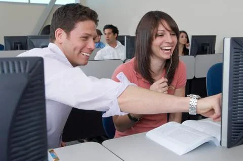 Happy Students Sitting Together At Computer Desk Foto stock